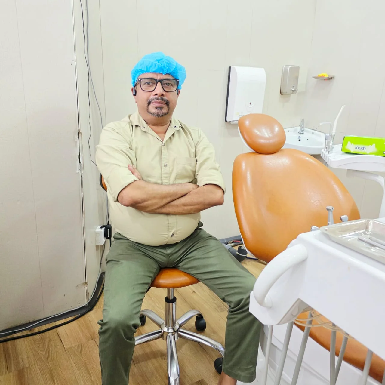 Dr. Jayasooriya seated beside the dental chair